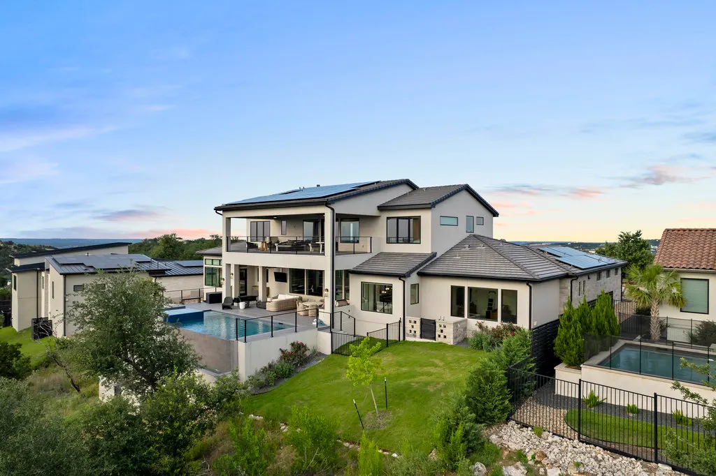 A Lakeway home and its lit pool from above at dusk