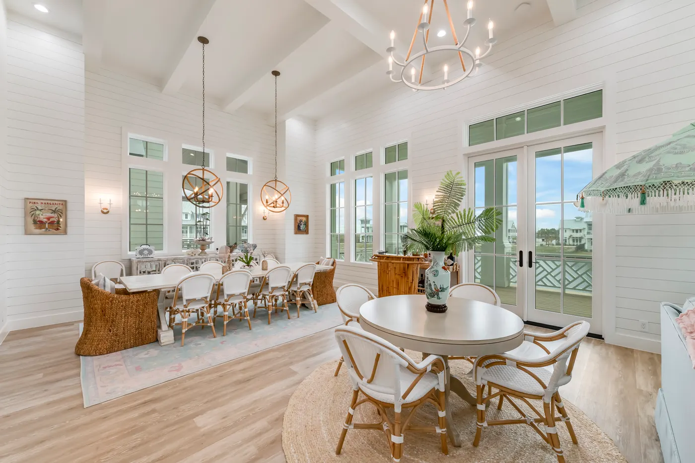 Vaulted living and dining under chandeliers in a coastal home