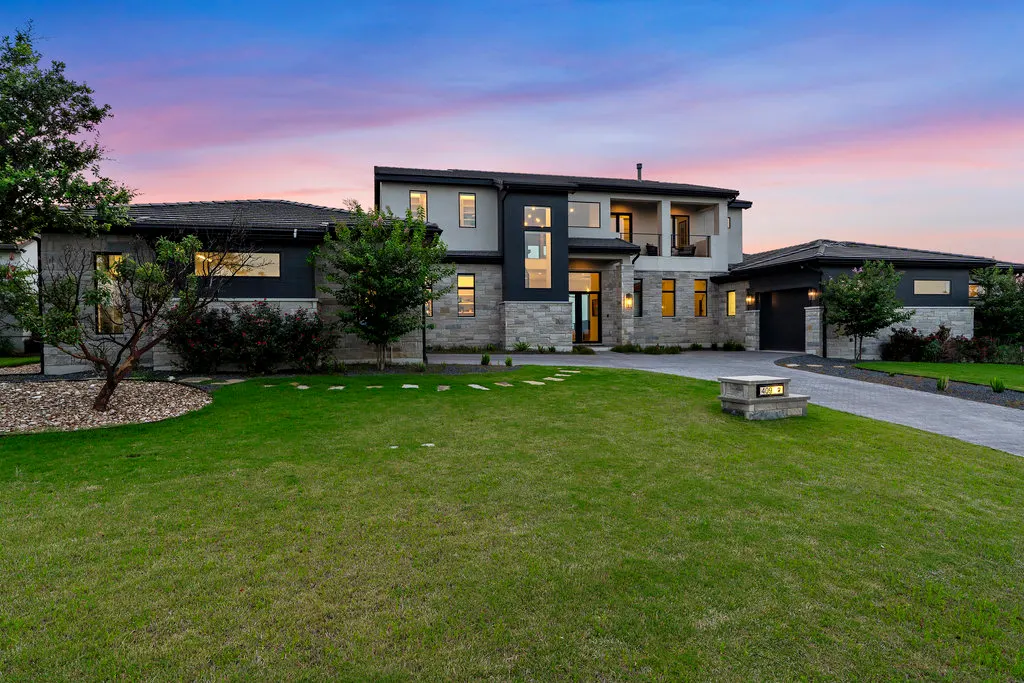 A backyard, terrace and lawn lit at dusk in the Hill Country