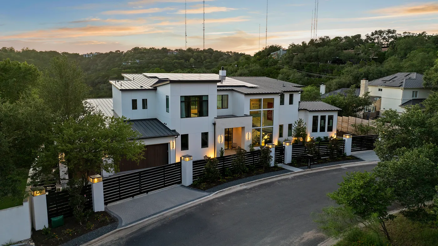 A modern Westlake residence at dusk behind a gated drive